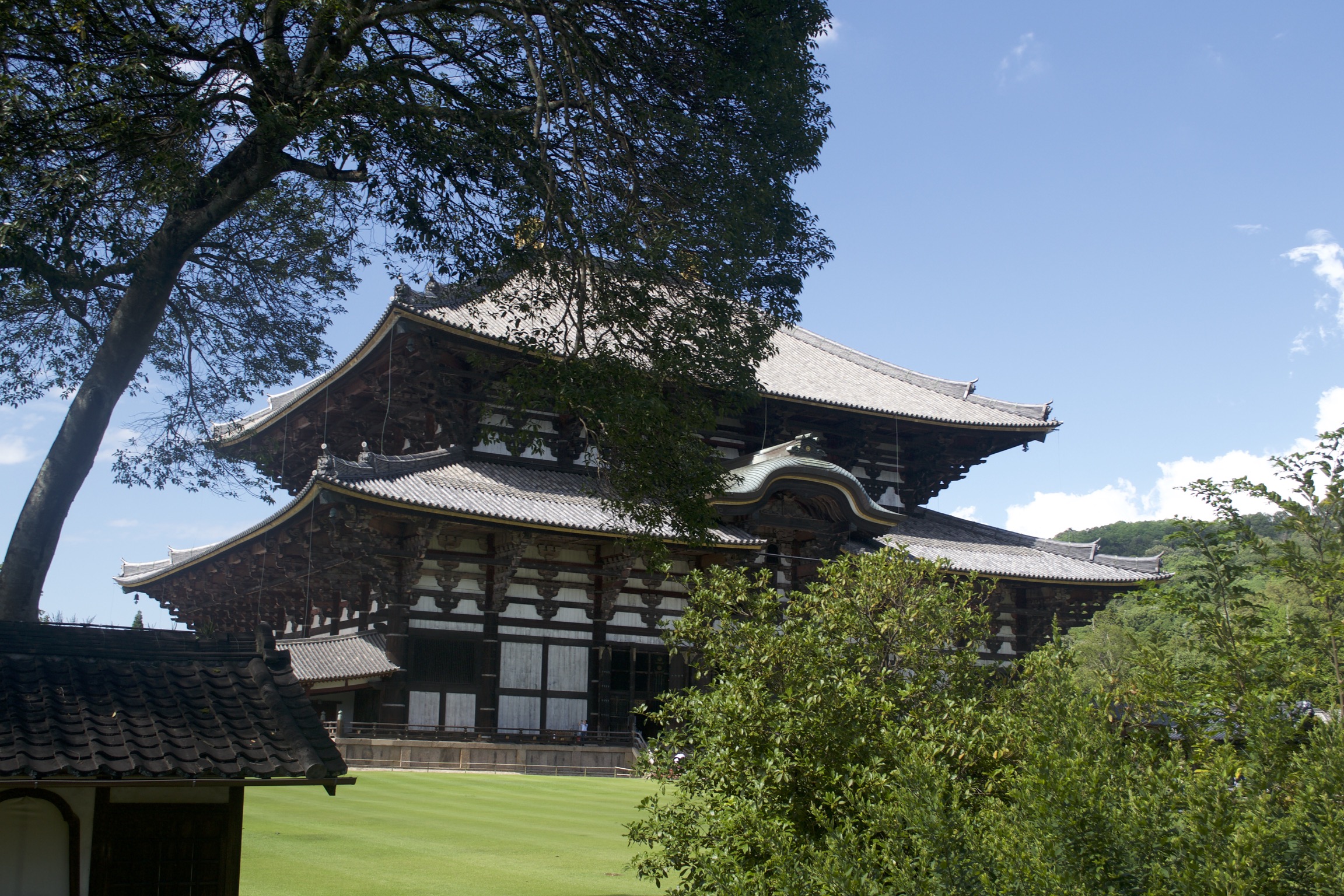 A huge Japanese building sits behind a perfect lawn.