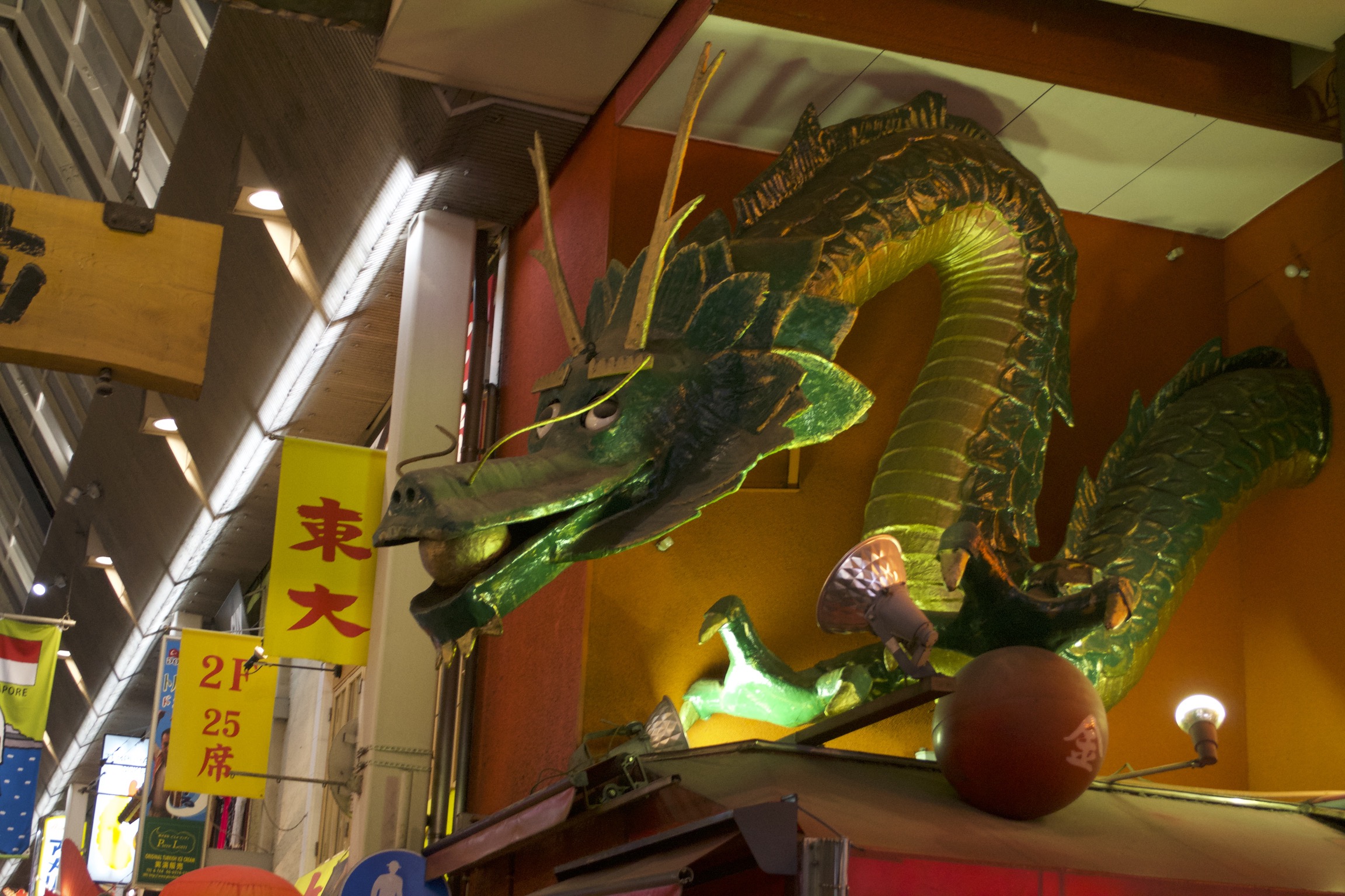 A painted green dragon statue sits atop a restaurant's entrance.