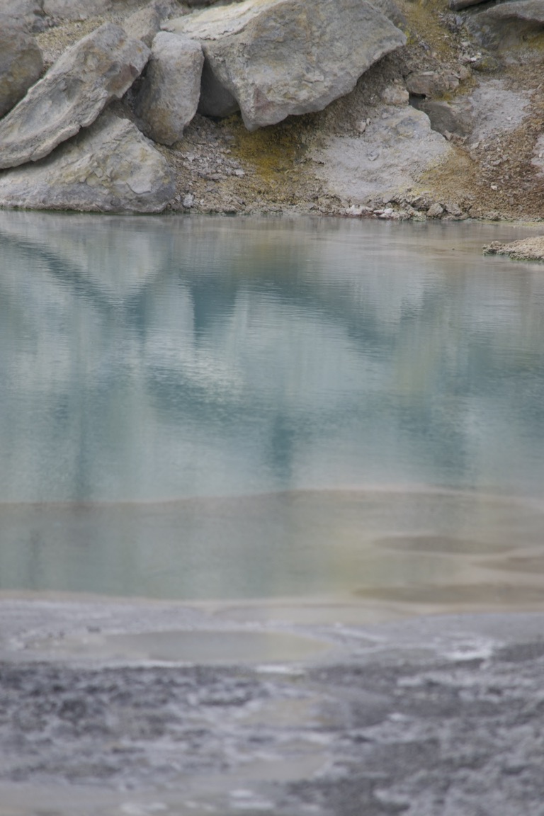 The reflections of gray and yellowed stones are reflected in an aqua pool.