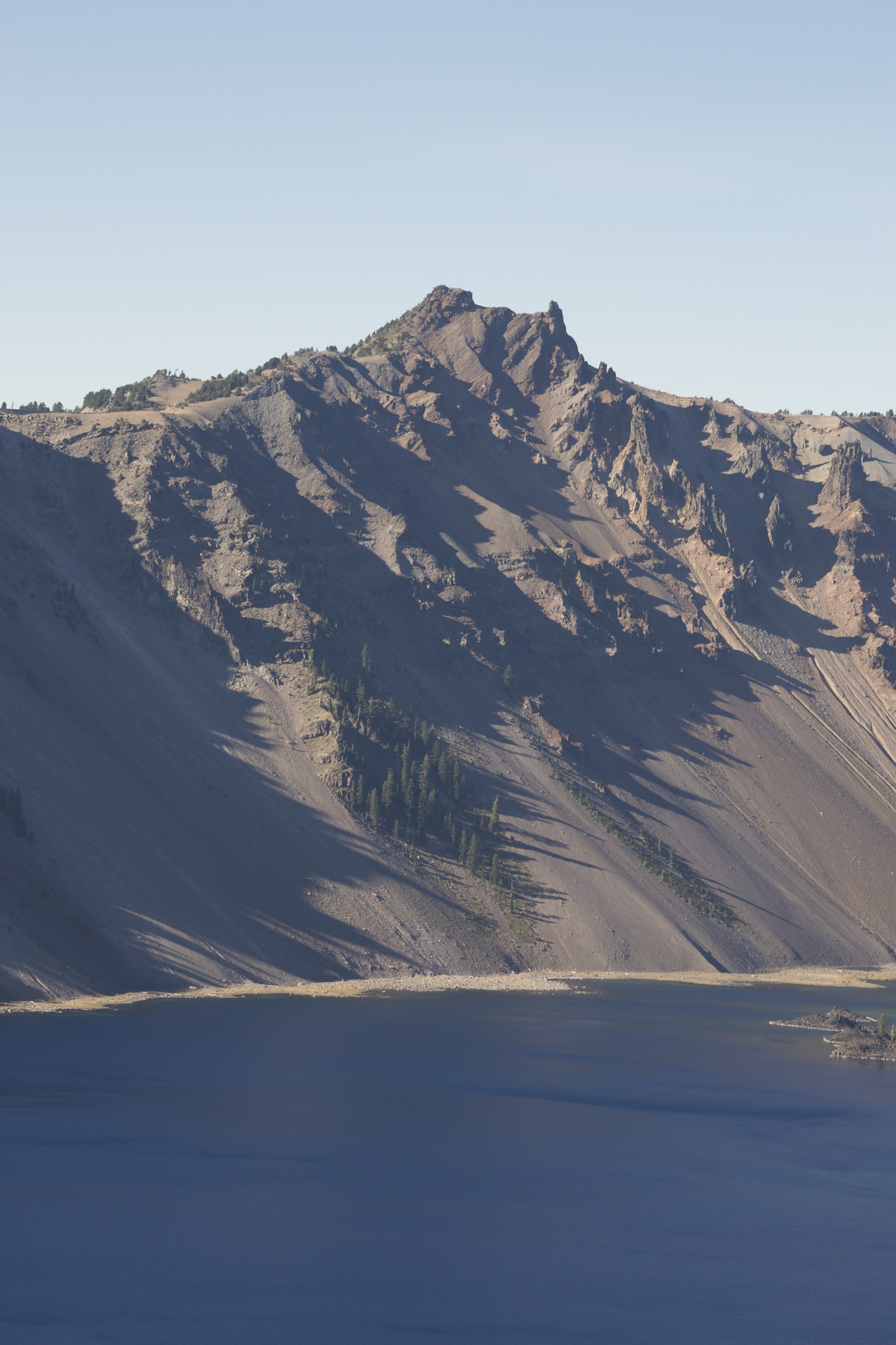 Rocky, mountainous, barren slopes meet the lake.