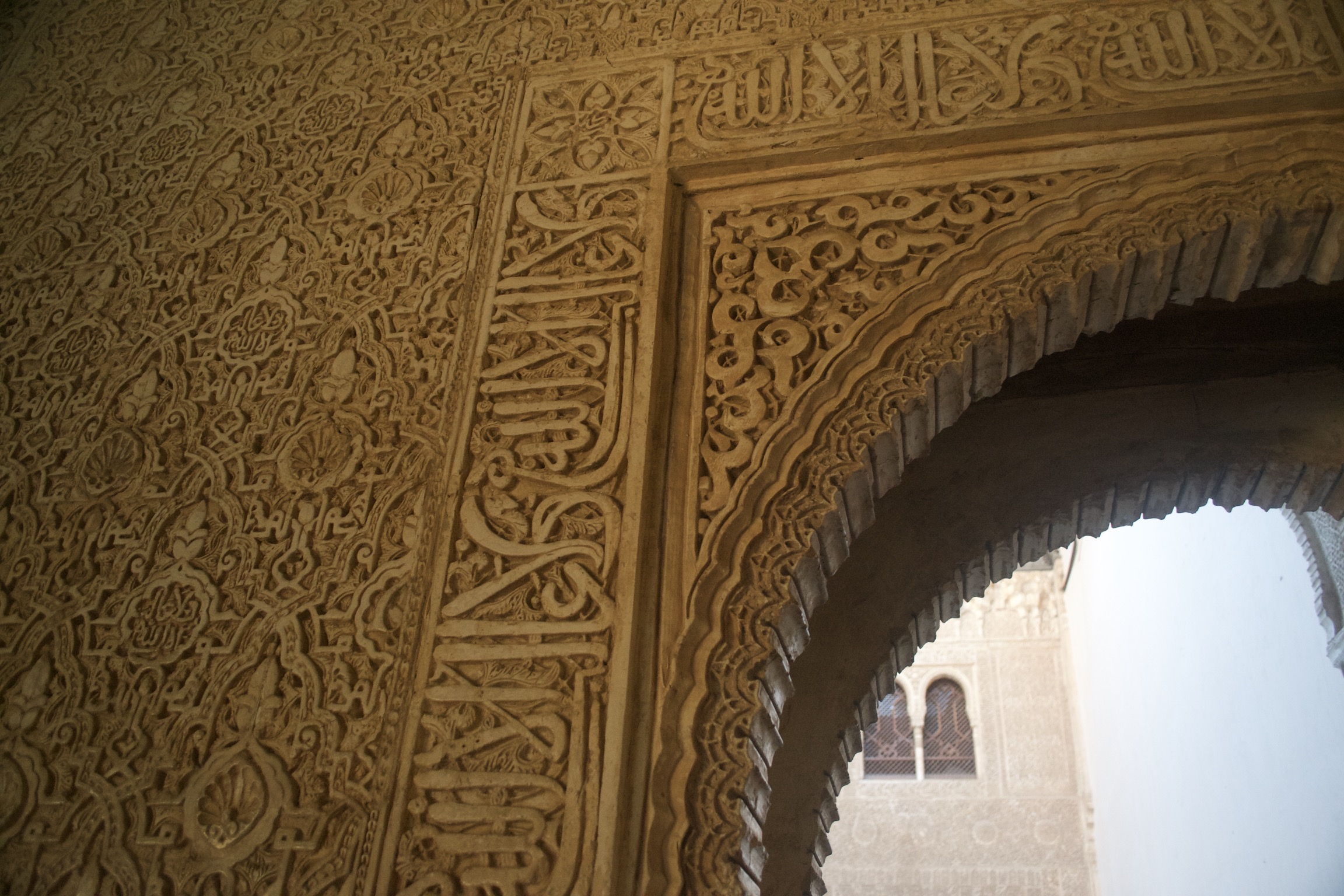 Details of the intricate designs and inscriptions on the wall surrounding an arched doorway.