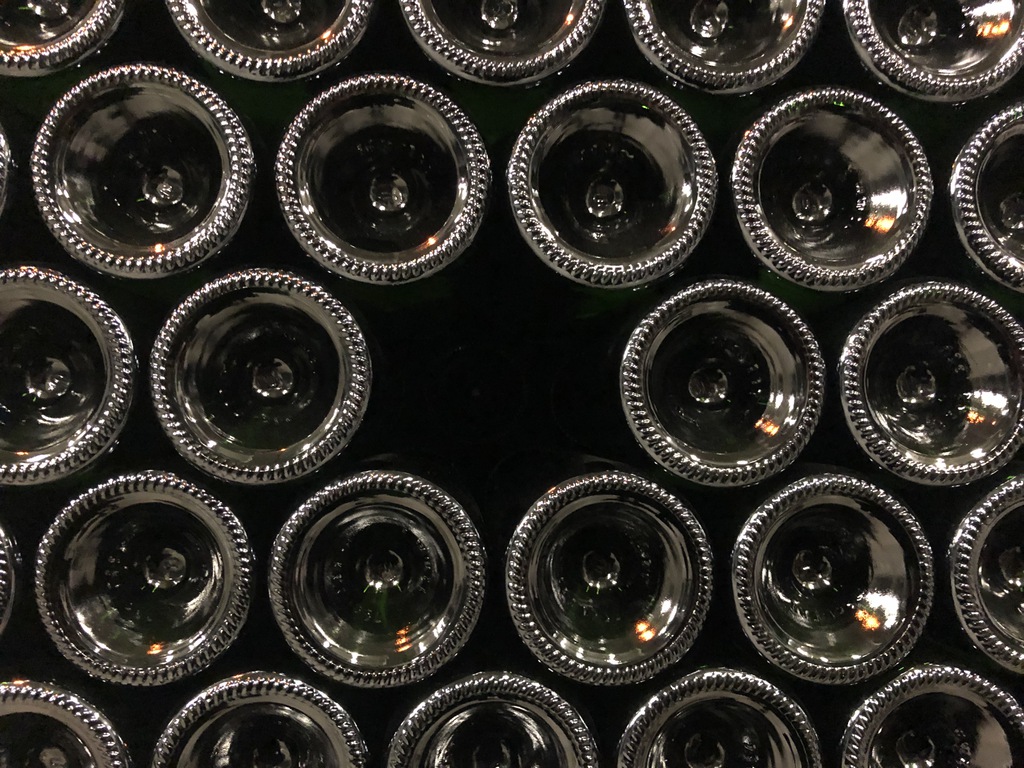 Bottoms of bottles of wine, stacked in a triangular lattice, with one bottole missing.