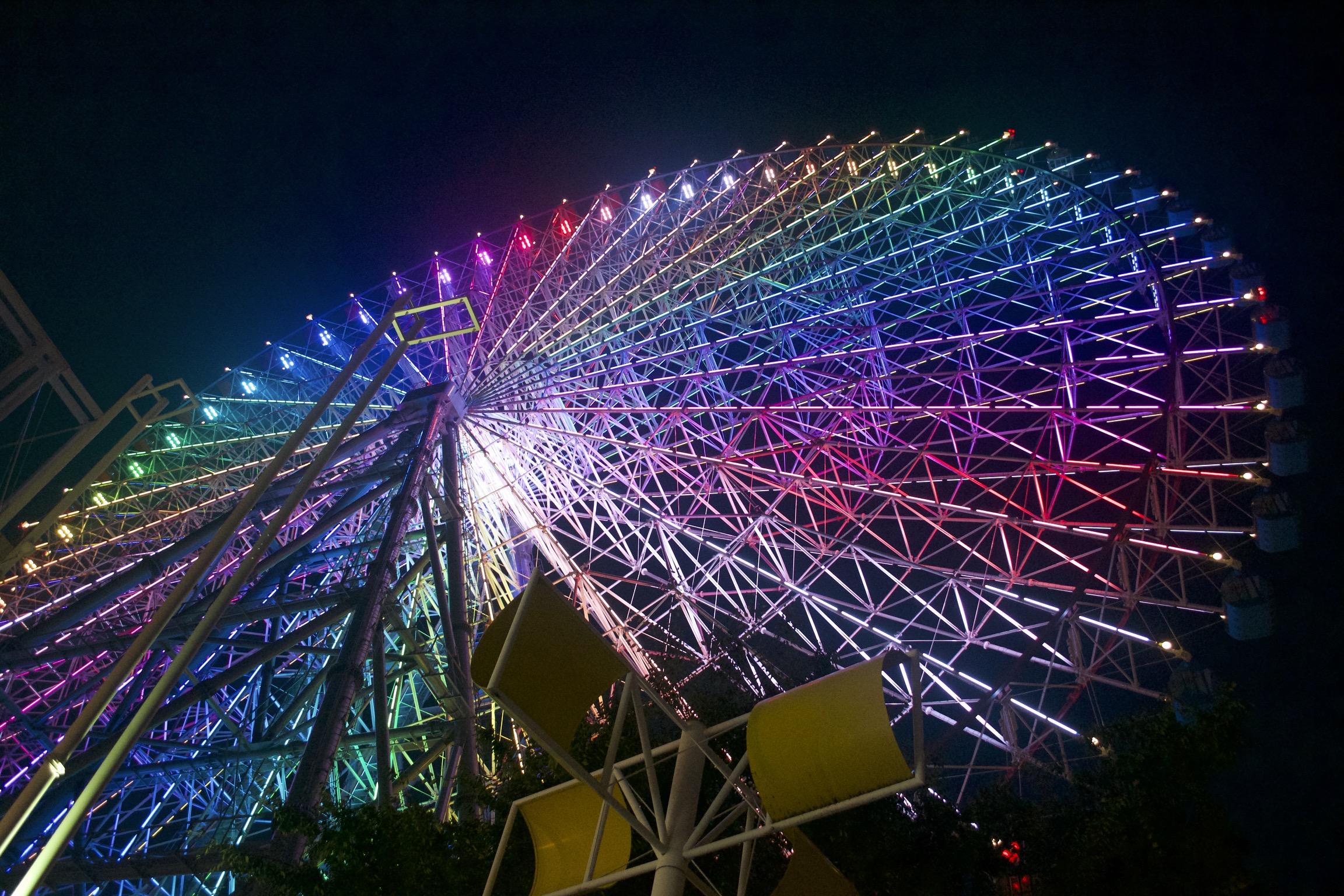A ferris wheel is illuminated with a rainbow of colors.