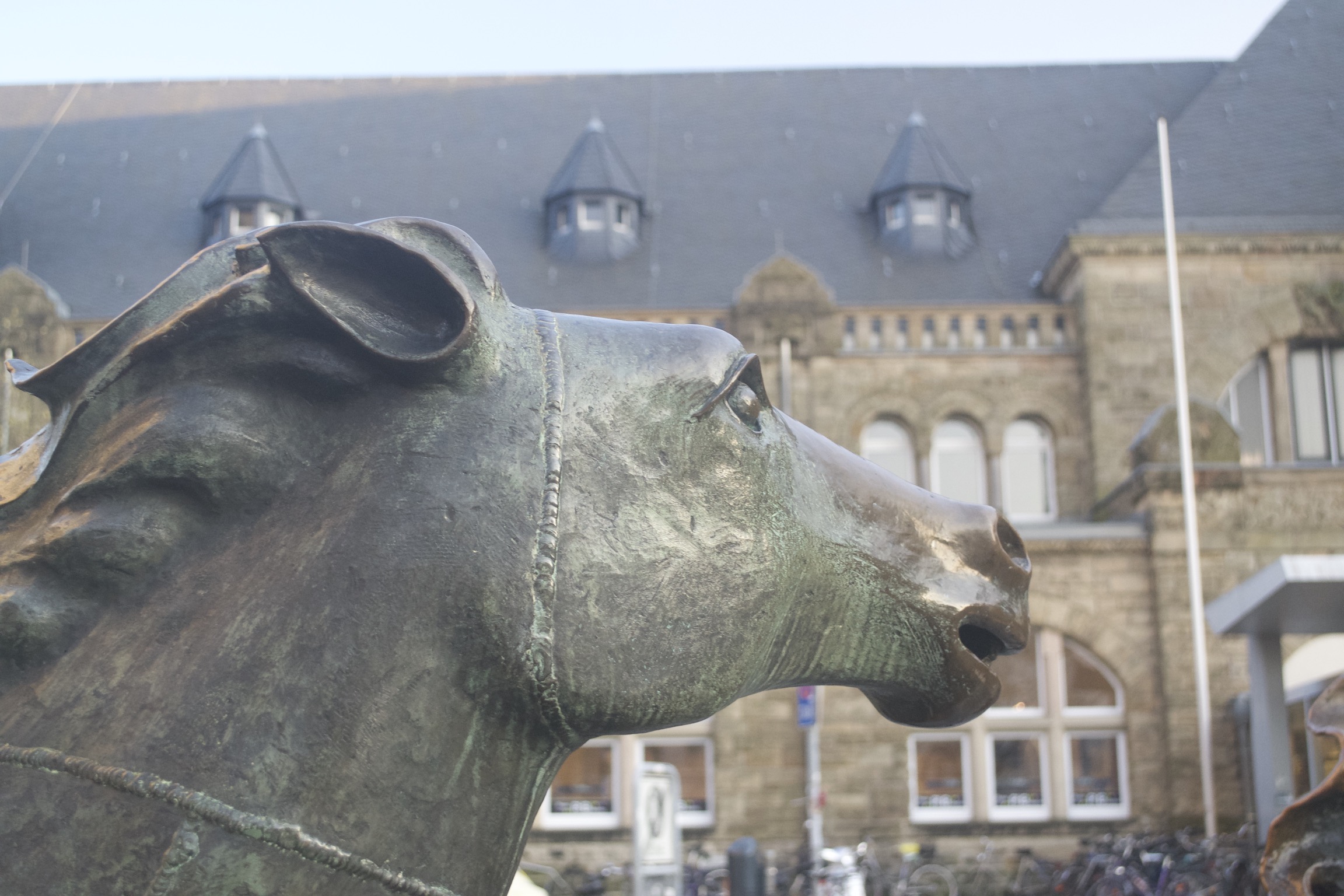 A horse statue in front of a brown train station.