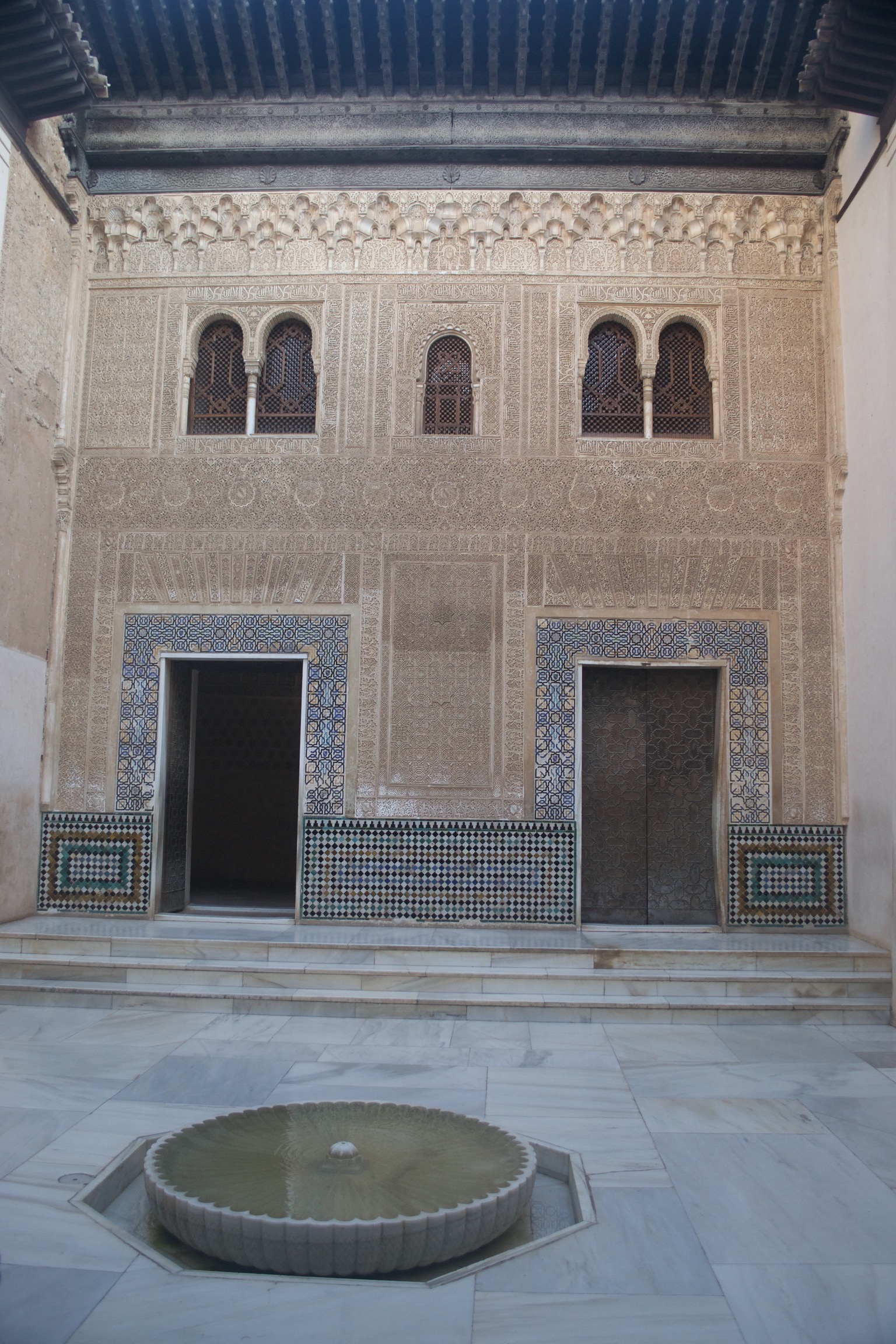 Two doorways are surrounded by mosaics.  The wall is covered with plastered molds or carved engravings.