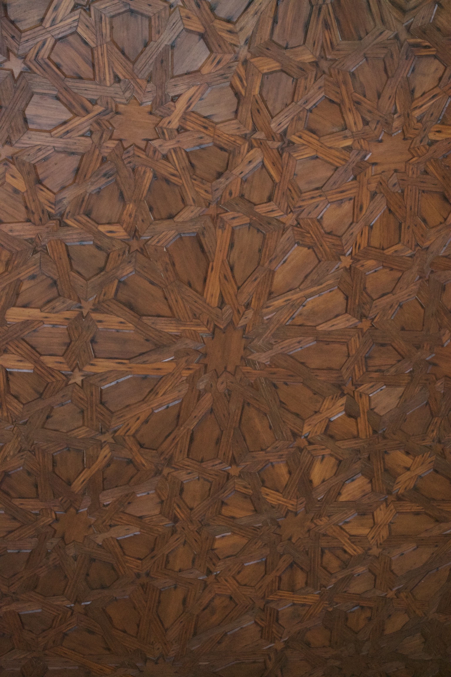 A geometric design of inlaid eight- and five-pointed stars that appear woven in wood.