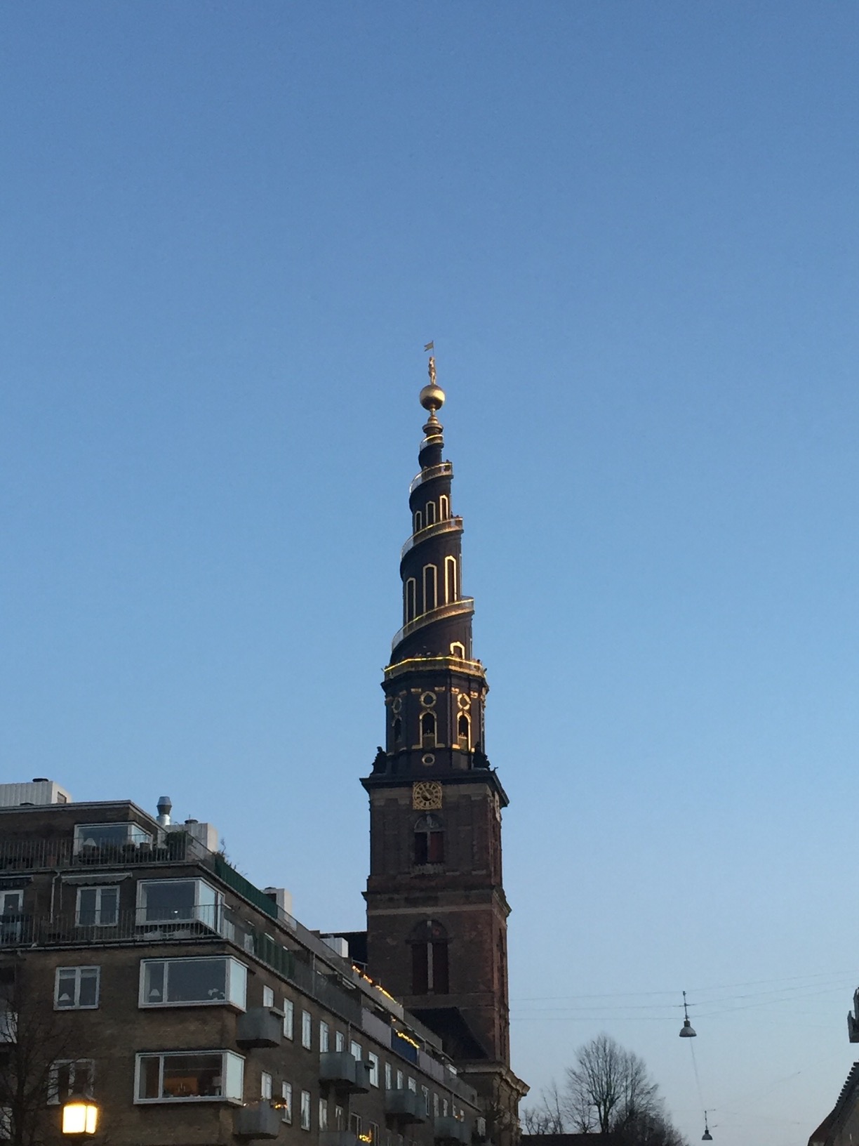 A black spiral spire trimmed with gold atop a stone tower.