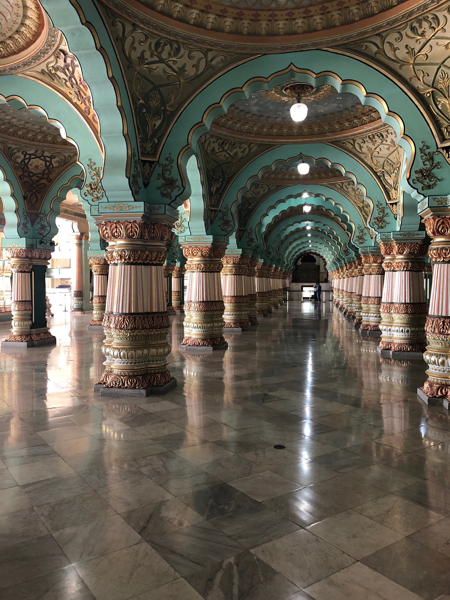 Rows and rows of teal scalloped archways supported by thick ornate columns on a granite floor of large square tiles.
