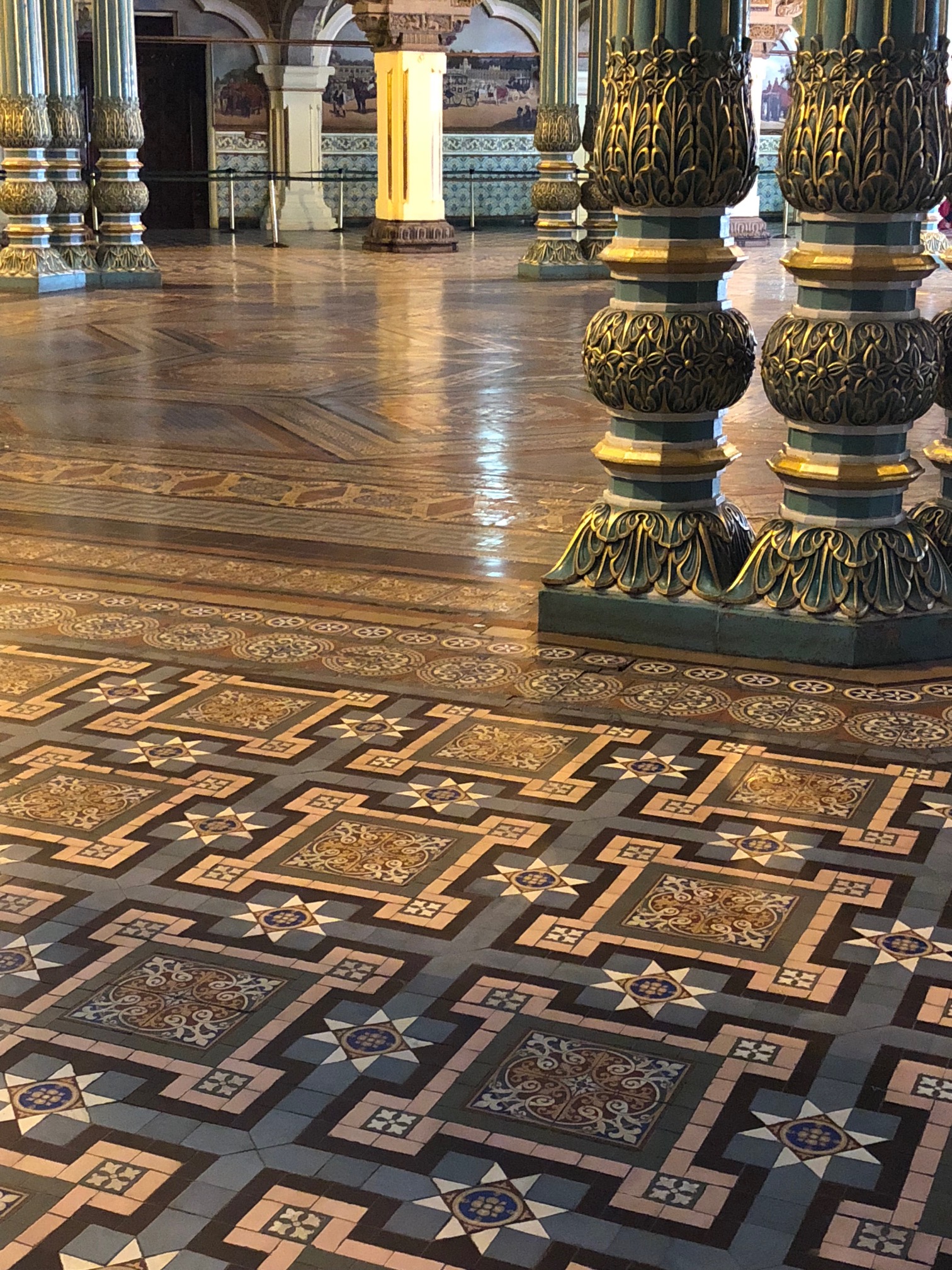 Green columns are painted with gold accents giving the impression of foliage surround a large tiled octagonal floor.